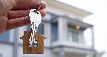 Person holding Keys in front of house