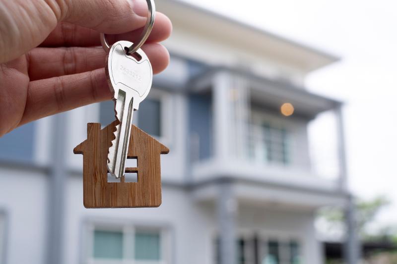 Person holding Keys in front of house
