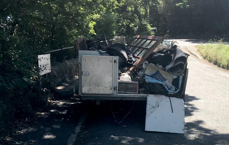 photo of a cut down caravan, which has been converted into a makeshift trailer filled with rubbish