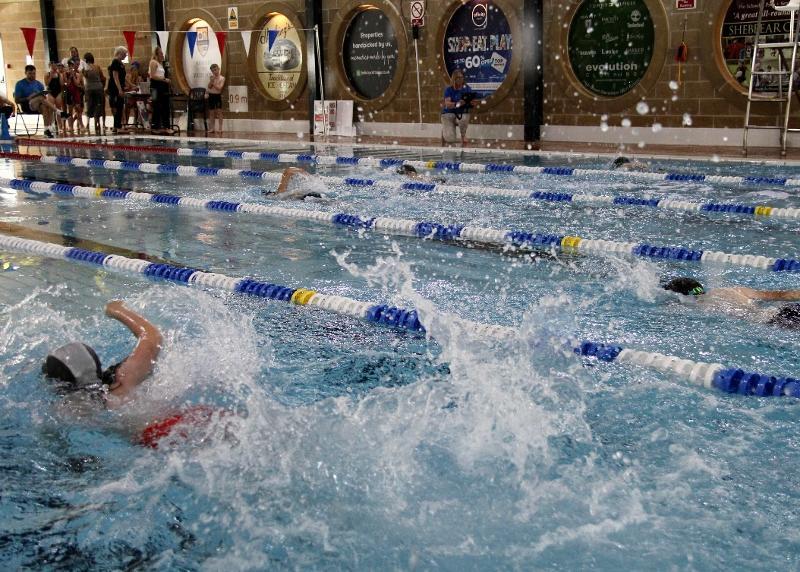 Photo of swimming pool lanes with people swimming in them, making a splash