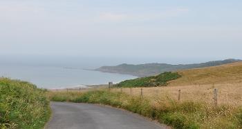 DCA 43: A road leading towards the sea with scrub on the coastal slopes