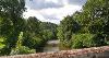 DCA 59: The River Taw passing under a stone bridge west of King's Nympton with dense deciduous woodland (Head Wood and Park Wood) on the valley sides.