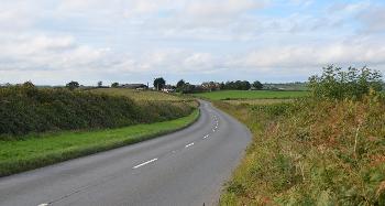DCA 63: View north-west along the A3124 north of Beaford. Large farm with new agricultural barns visible as well as a traditional thatched cottage. 