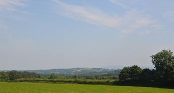 DCA 65: A distant view of Dartmoor from south of Shebbear, across farmland with a dense hedgerow network and extensive areas of woodland.