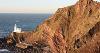 Figure 2.18: A photograph of a lighthouse on a promontory below rocky cliffs.