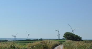 Figure 2.22: Wind turbines on a landscape with fields, hedgerows and a road in the foreground.