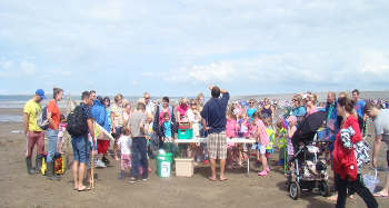 Photo of children and their families listening to the Ranger on the beach before going off to the rockpools