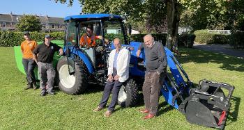 photo of a blue tractor with Councillor Bob Hicks and Councillor Chris Leather leaning against it, and Robyn, Sam and John from Torridge District Council's Grounds Maintenance Team