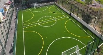 Image of a new football pitch with two goals at either end and a bright green floor with white and yellow line markings 