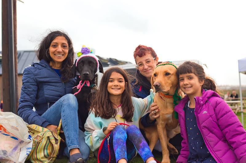 Image of multiple people smiling for the camera with a couple of dogs