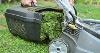 Picture of someone taking the back off a lawn mower, showing all the cut grass inside