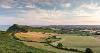 Scenic view across fields with cloudy blue sky