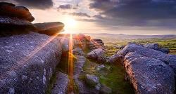 Photo of big rocks in a field with the sun shining through.