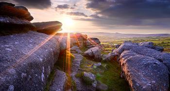 Photo of big rocks in a field with the sun shining through.