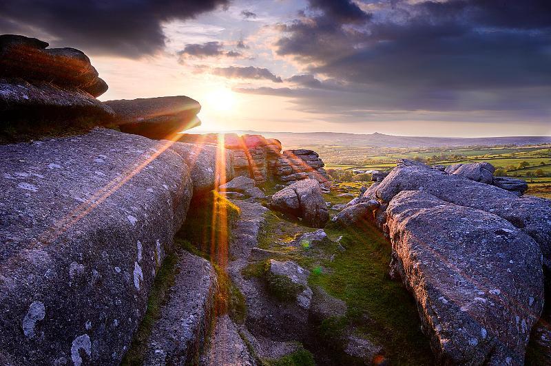 Photo of big rocks in a field with the sun shining through.