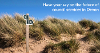 A photo of a walking path sign on some sandy dunes with the text 'have your say on the future of council services in Devon' across the blue sky. 