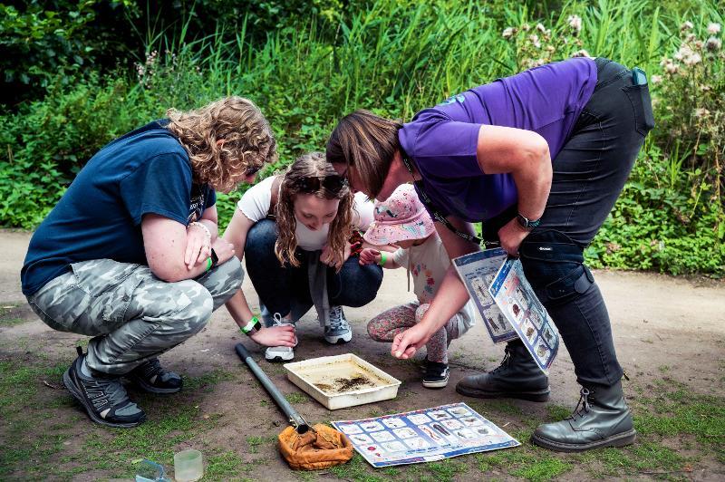 Group of people huddled over a tray looking at animals and organisms inside it