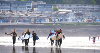 A group of surfers at Westward Ho! walking along the sand with the sea behind them